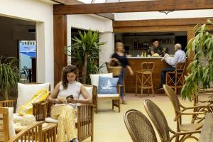 una mujer sentada en una silla mirando un libro en Camping La Davière Plage - Maeva, en Saint-Jean-de-Monts