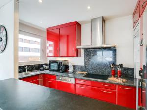 a kitchen with red cabinets and a black counter top at Tignes - Appartement chaleureux 3 pièces, 8 pers., pied des pistes, proche commerces, WiFi - FR-1-411-48 in Tignes +8 photos