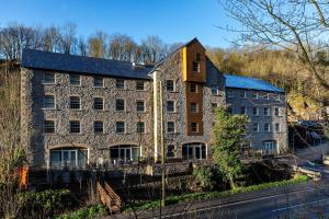 an old stone building on the side of a street at Rock Mill Studio Apartment 18 in Stoney Middleton