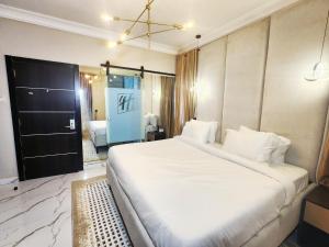 a bedroom with a large white bed and a bathroom at Ihsuites in Asaba