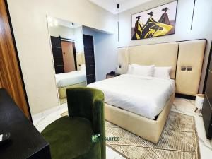 a bedroom with a bed and a chair and a mirror at Ihsuites in Asaba