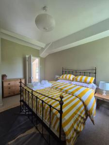 a bedroom with a bed with yellow and white stripes at Little Plas in Crickhowell