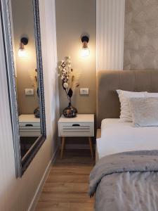 a bedroom with a bed and a mirror and a vase with flowers at ALDIRA Studio Arena Nationala in Bucharest