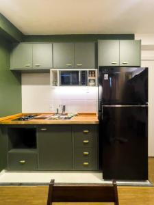 a kitchen with green cabinets and a black refrigerator at Tropical apartament in Sao Paulo