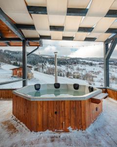 a jacuzzi tub in the snow with a view at Casa Bella Vlădeasa in Săcuieu