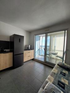 een keuken met een koelkast en een balkon met een tafel bij T2 vue port de Sete in Sète