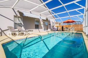 a swimming pool with chairs and an umbrella at Family Villa Destination in Davenport