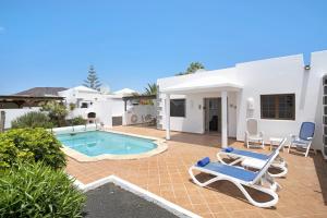 a villa with a swimming pool and two lounge chairs at Casa Calma in Playa Blanca