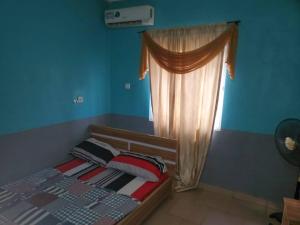 a bedroom with a bed with a curtain and a window at ATEWO HERITAGE HOTEL, ilogbo ekiti, Ekiti state in Usi +2 photos