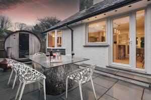 Un patio con mesa y sillas y una casa. en Woodlands Family Retreat Windermere with Hot Tub and Sauna, en Windermere