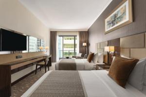 a hotel room with two beds and a flat screen tv at Hawthorn Extended Stay by Wyndham Abu Dhabi City Center in Abu Dhabi