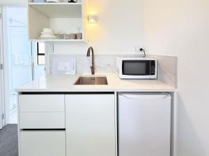 ロトルアにあるUnit 1, Fenton Summer Lodgeのシンクと電子レンジを備えた白いキッチン