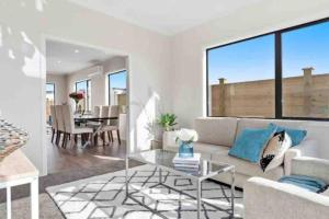 a living room with a couch and a glass table at Modern Beach Retreat 4 bedrooms in Papamoa