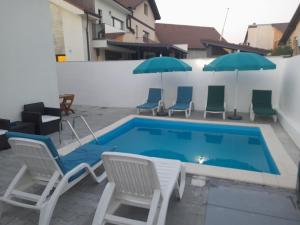 a swimming pool with lawn chairs and umbrellas at Regim Hotel Hanea jacuzzi in camera,piscina exterioara si sauna comuna in Sibiu