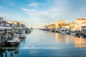 un groupe de bateaux amarrés dans un canal avec des bâtiments dans l'établissement AS18262 - Studio en Centre Ville, au Grau-du-Roi