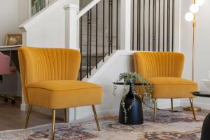 two yellow chairs in a living room with a staircase at 3 Bedroom Detached Home with Free Parking, Netflix, Free Banff Pass, King Size Bed & Portable AC in Balzac