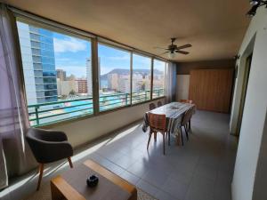 a dining room with a table and chairs and a large window at Amaika, cerca de playa, con aparcamiento y piscina in Calpe