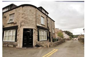 an old stone building with a black door on a street at Cosy Flat in Y Felinheli in Y Felinheli