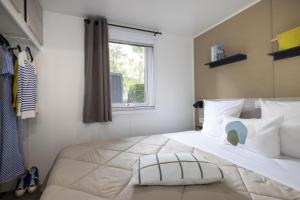 Un dormitorio con una gran cama blanca con ventana. en Camping La Davière Plage - Maeva, en Saint-Jean-de-Monts 20 fotos más