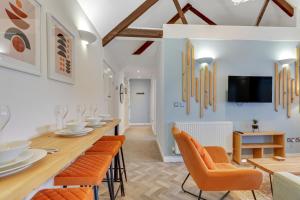 a dining room with orange chairs and a long table at Chai at The Tea Warehouse - North East Escapes in Alnwick