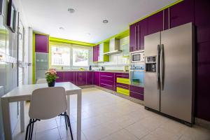 kuchnia z fioletowymi szafkami, stołem i lodówką w obiekcie Villa Cañada torremolinos w mieście Torremolinos
