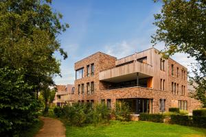 an external view of a brick building with trees at Dormio Resort Maastricht Castellum Apartments in Maastricht