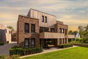 a brick building with a balcony on a lawn at Dormio Resort Maastricht Castellum Apartments in Maastricht +8 photos