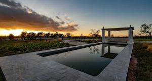 a swimming pool with a gazebo and a sunset at Trulli Mansueto in Noci