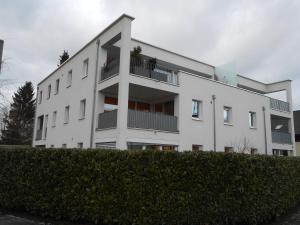 a white apartment building with a hedge in front of it at Ferienwohnung Daniela in Höchst