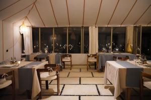 a restaurant with tables and chairs and a large window at Luxury berber style in Merzouga