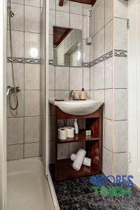 a bathroom with a sink and a mirror and a shower at Moinho Pedra Pomes in Santa Cruz da Graciosa