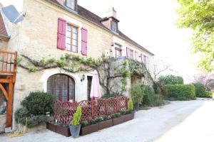 a building with pink shutters and ivy on it at Gites le Sud, La Petite Grange in Puybrun