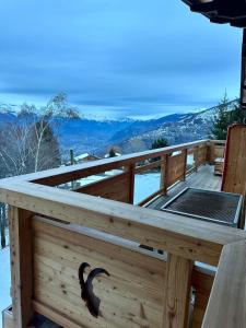 a wooden deck with a table with a view of the mountains at Chalet Le Bouquetin avec jacuzzi et sauna in Nendaz
