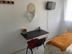 a bedroom with a black desk and a red chair at Appartement T3 individuel avec accès piscine et jardin privés in Basse-Goulaine