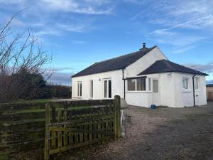 una casa bianca con una recinzione davanti di Mains of Greenlaw Cottage a Castle Douglas