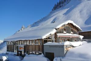 ein schneebedecktes Gebäude vor einem Berg in der Unterkunft Lari Fari in Faschina