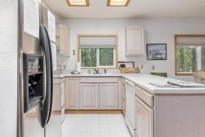 a kitchen with white cabinets and a stainless steel refrigerator at Twin Maples | WiFi, River Access, BBQ in Packwood