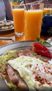 a table with a plate of food and two glasses of orange juice at Arvi Rooms in Lukovë +10 photos