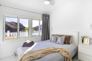 a white bedroom with a bed and windows at House of dreams in Mogán +25 photos