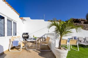 a patio with chairs and a potted palm tree at House of dreams in Mogán