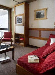 ヴァル・トランスにあるAbrineige Clubhotel Le Gypaète Val Thorensのリビングルーム(赤いベッド1台、テーブル付)