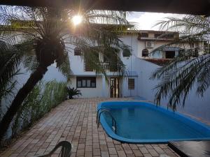 a swimming pool in front of a house with a palm tree at INTEIRO com 3 SUITES E PISCINA in Foz do Iguaçu