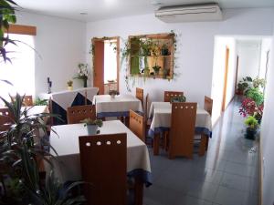 a restaurant with white tables and chairs and plants at Hotel Residencial Ermida dos Remédios in Lajes