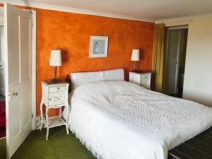 a bedroom with a white bed with an orange wall at Kildare in Niton