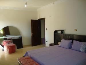 a bedroom with a bed with purple sheets and a mirror at Villa High Town Al Shuruq City in Madīnat ash Shurūq