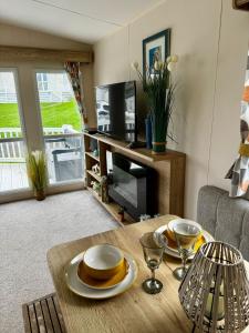 a living room with a table with plates and glasses at PV70 newquay bay resort in Newquay Bay Resort +17 photos