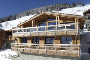 a log cabin in the snow with a large deck at Odalys Chalet Le Panda in Les Deux Alpes