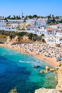 a beach with people in the water and buildings at Carvoeiro Terrace by Homing in Carvoeiro