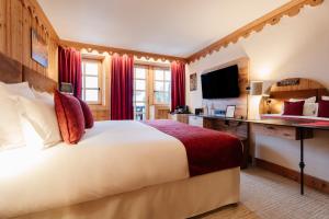a hotel room with a large bed and a television at La Ferme du Golf in Megève +127 photos