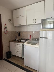a kitchen with white cabinets and a white refrigerator at Kitnet Asa Sul in Brasilia +5 photos